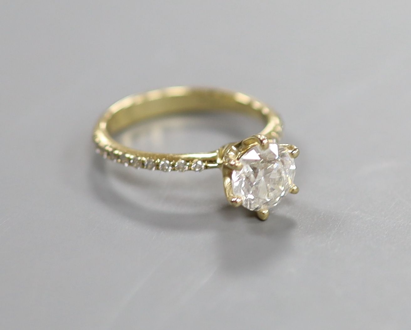 A modern 14kt yellow metal and single stone diamond ring, with diamond chip set shoulders